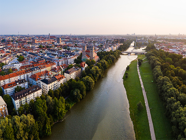 Aerial view of Munich with a river, trees and a walking path alongside the river.
