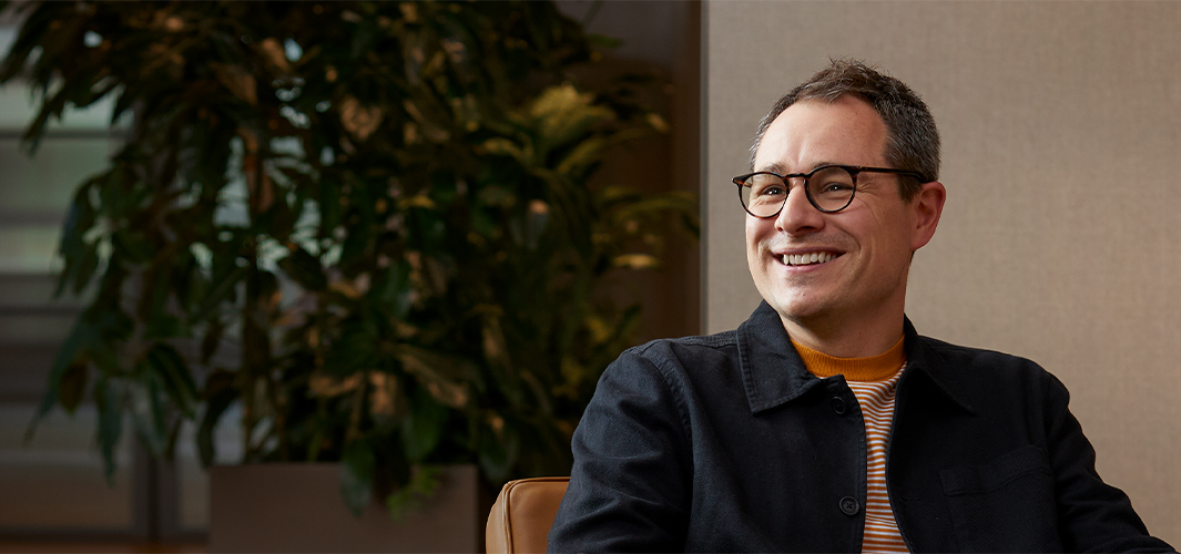 Dan sitter i en fåtölj och ler och tittar på någon till höger.