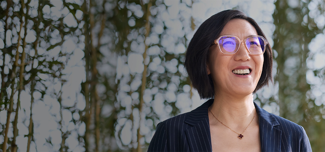 Ella ler och tittar uppåt framför en vägg med växter.