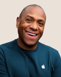 Portrait of a smiling Apple Retail team member with short, dark grey hair.