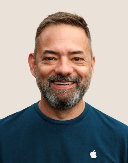 Portrait of a smiling Apple Retail team member with short grey hair and a beard.