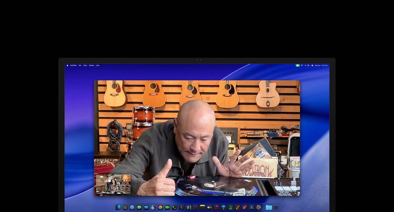 Durante una videollamada, una persona en una tienda de música mira de cerca un tocadiscos y permanece en el centro de la imagen gracias a la cámara Center Stage