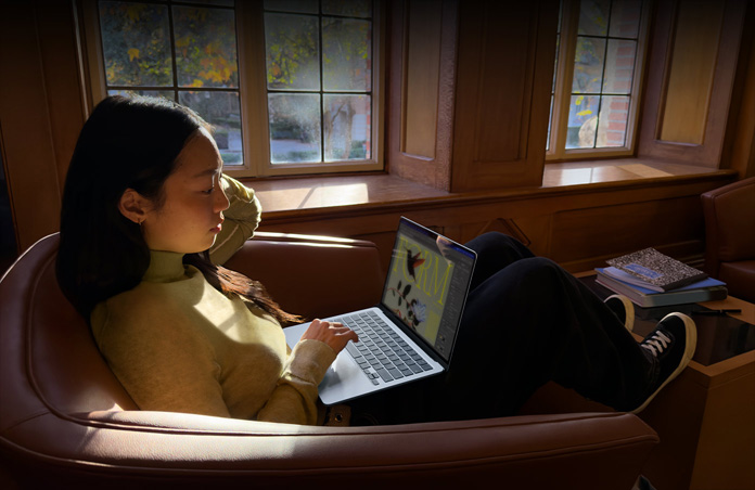 A person sitting in a chair using their MacBook Air