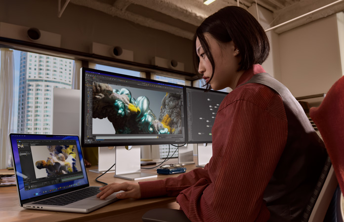 شخص يعمل في مكتب بجهاز MacBook Pro متصل بشاشة Studio Display XDR