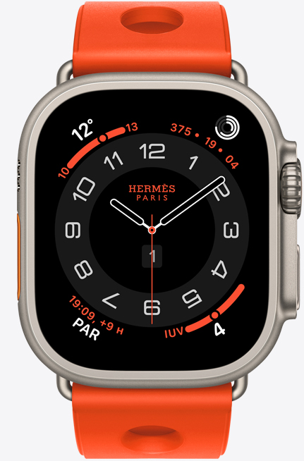 Apple Watch Hermès Ultra 3, carátula analógica Circulaire, (agujas de hora, minuto y segundo, complicaciones: Clima, círculos de Actividad, hora de París e Índice UV), caja de titanio, color natural, parte lateral derecha, Digital Crown, botón lateral en relieve, con la correa Scub'H Diving, color Orange Néon (naranja brillante), fabricada con goma moldeada, aberturas circulares en el centro