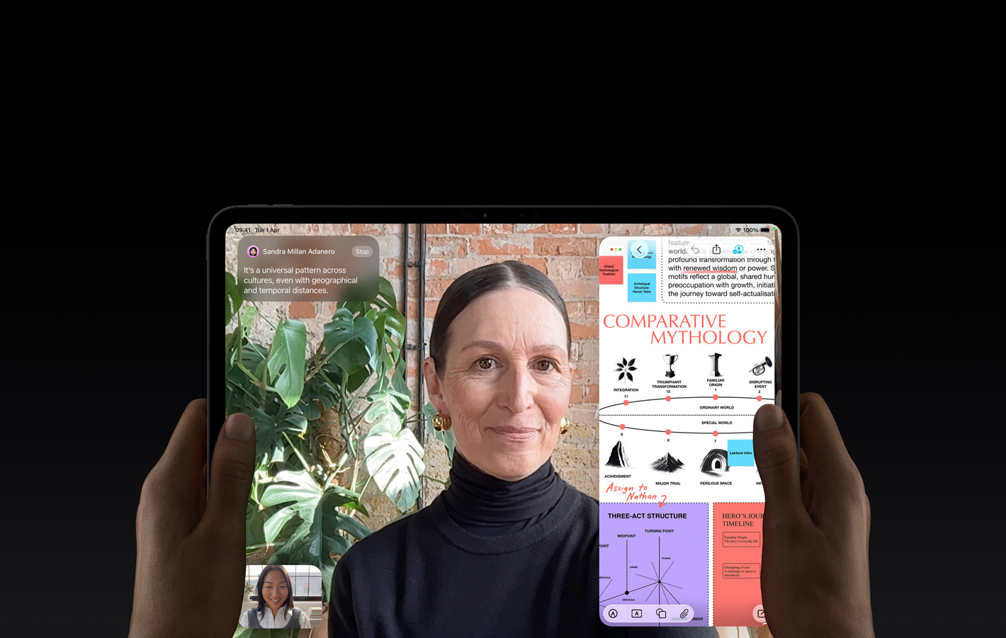 iPad Pro, front exterior, space black color, left and right hands holding in landscape orientation, rounded corners, black display bezel, display showing a FaceTime conversation being live translated, and an educational app showing a presentation of 'Comparative Mythology' with text, diagrams, and handwritten notes