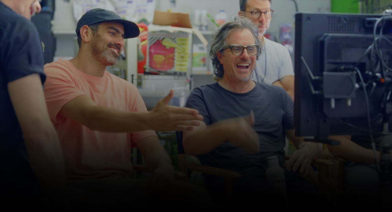 Image de deux cinéastes assis en train de regarder un écran de projection et de faire des gestes dans sa direction.