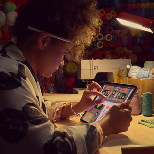 Masada oturan bir kişi, iPad’in ekranındaki görseli iki parmağını kullanarak yakınlaştırıyor.