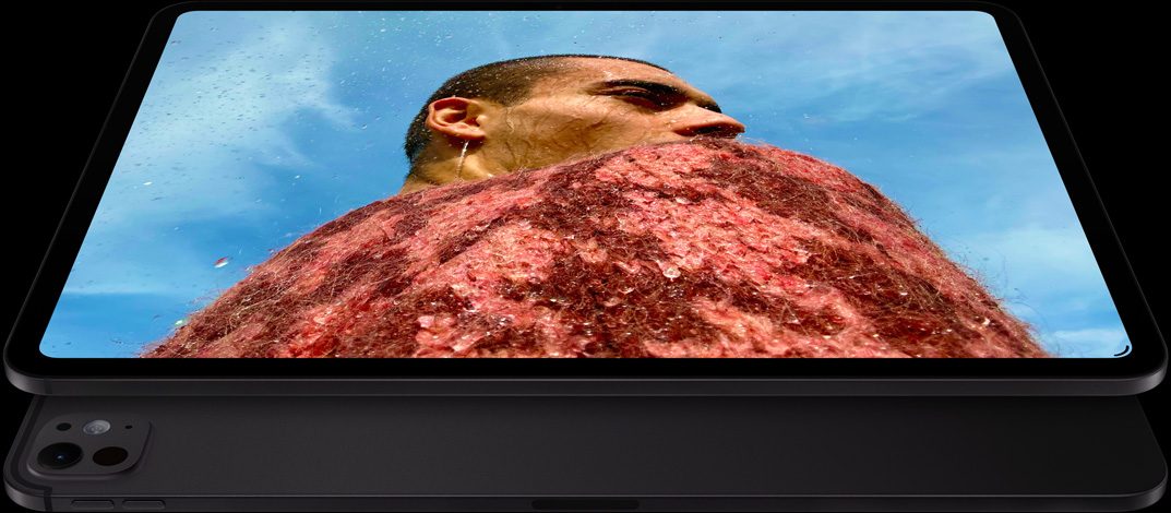 iPad Pro, front side exterior, landscape orientation, space black colour, rounded corners, black display bezel, display showing a photo of a man in a red jumper under a blue sky, underneath, another iPad Pro, back exterior, landscape orientation, space black colour, pro camera system, volume-up button, volume-down button